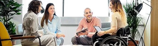 Small group of happy colleagues talking with fellow colleague in wheelchair.