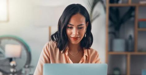 Woman sitting at a desk looking at a laptop.