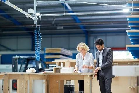 Young businessman and senior female manager looking at paperwork in factory