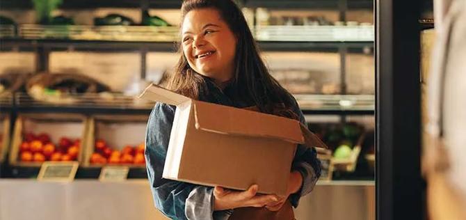 Young woman with Down syndrome working in a store smiling.