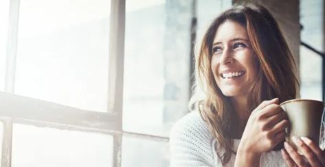 An attractive young woman drinking coffee and relaxing at home