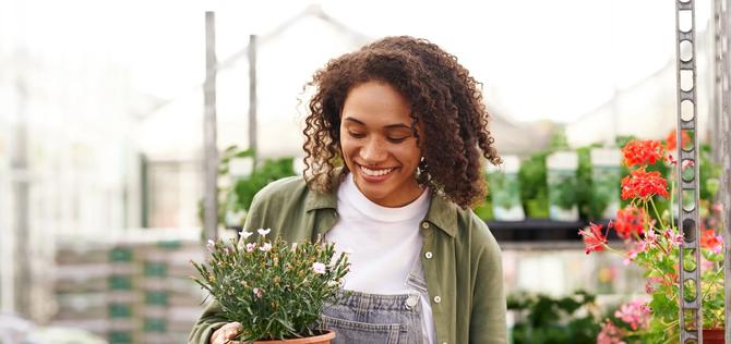 Professional woman garden worker transplants plants and takes care of flowerpots in botanic shop
